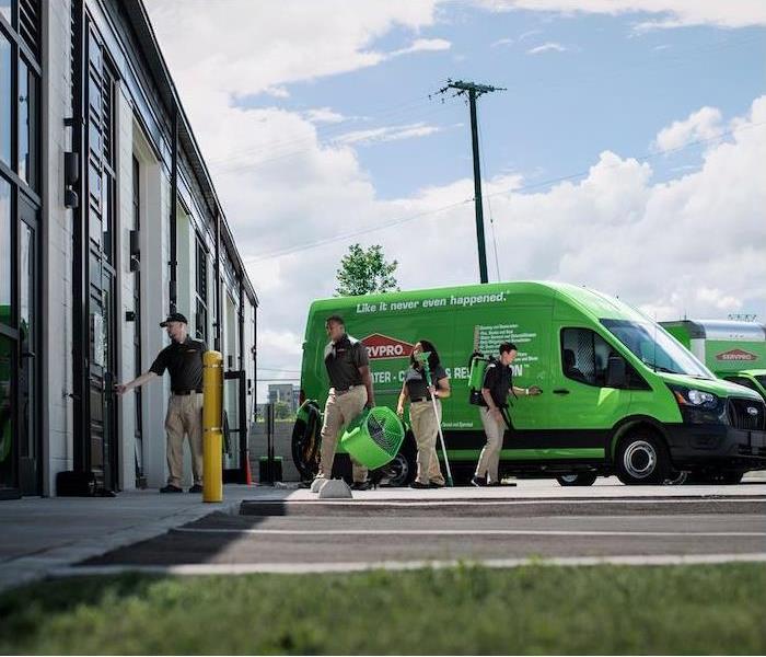 "a group of employees with restoration tools walking away from SERVPRO van" 